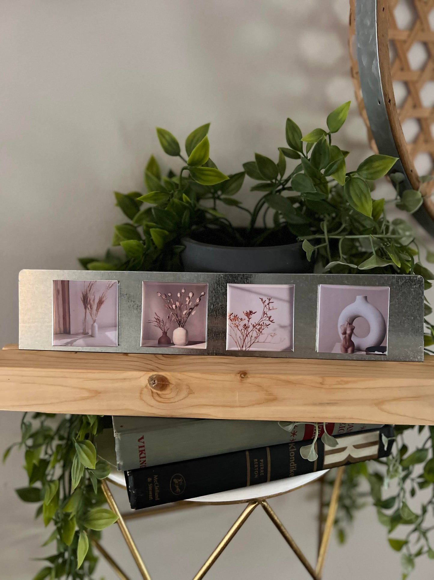 Decorative photo stand with four small photo magnets on a wooden shelf with plants in the background.