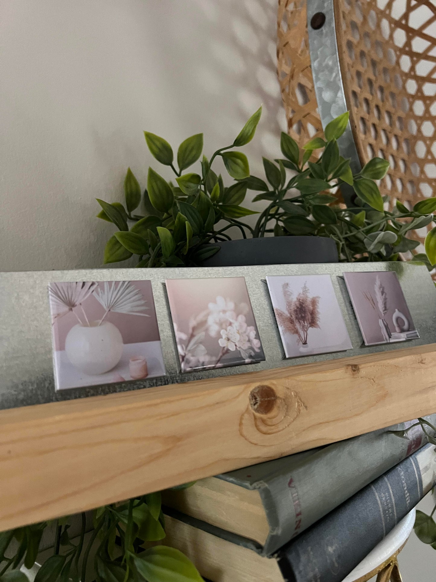Small aesthetically pleasing prints on a wooden stand magnet display with books and plants