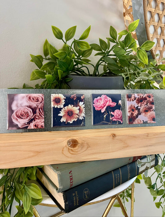 Decorative photo stand with magnets displayingwith floral designs on a shelf with books and plants.