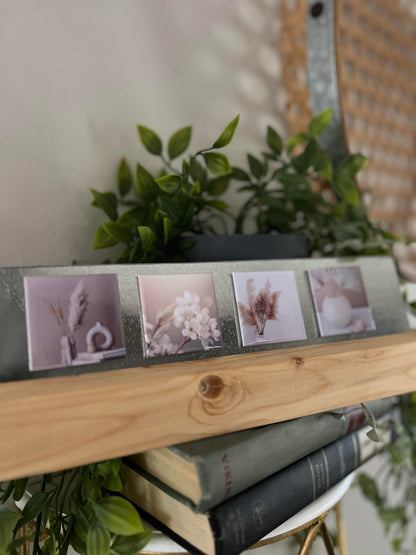 Small photo square magnets on a wooden shelf with plants in the background
