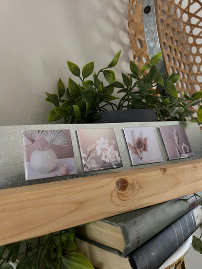 Small aesthetically pleasing prints on a wooden stand magnet display with books and plants