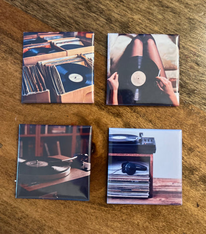 Four square magnets with vinyl record-themed vinyl images on a wooden surface
